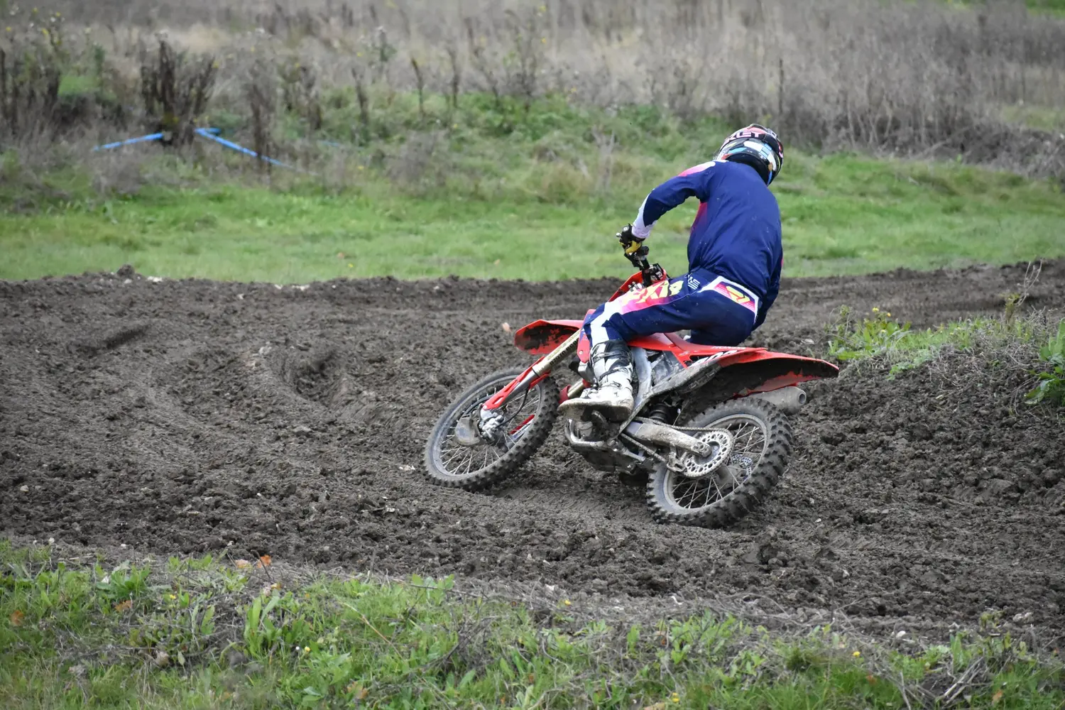 Motocross rider leaning into a muddy turn